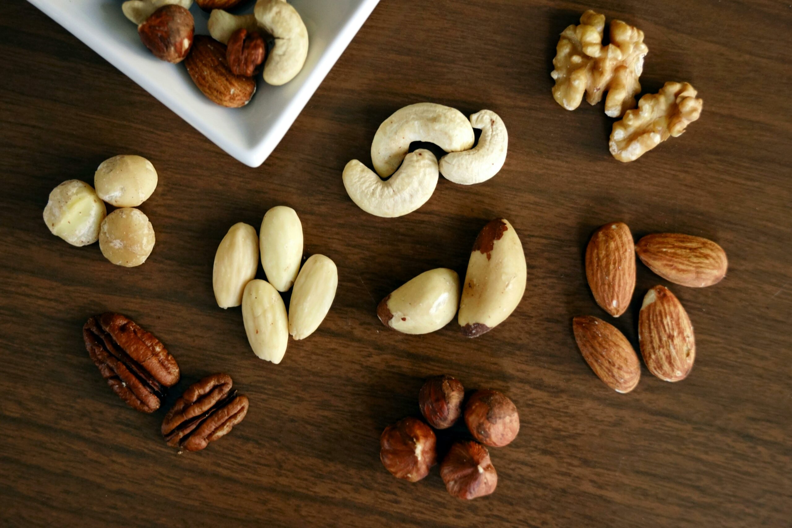 Home Close-up of various nuts on a wooden table, showcasing healthy snacking options.