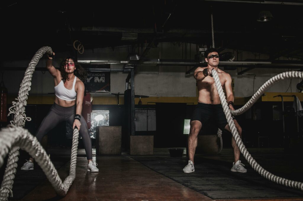 Home Two people engage in a powerful indoor battle rope workout, showcasing strength and energy.